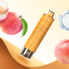 A peach-flavoured vape device placed on a textured leather surface, surrounded by fresh peaches, a peach slice, green leaves, and ice cubes, with a soft gradient background.