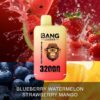 A packaging design for a vape product featuring a yellow container labeled "BANG LEADER" with an illustration of a monkey wearing glasses. The label states the flavors "Blueberry Watermelon & Strawberry Mango" and "32,000 PUFFS." The background includes splashes of strawberries, watermelon, and blueberries, enhancing the fruity theme.