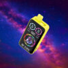 Rectangular electronic device with a yellow outer casing and a black digital display, featuring colourful illuminated visuals and branding, set against a cosmic background with vibrant nebulae and stars.