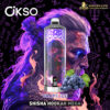 A vape device with a reflective, patterned surface overlaid on an artistic background of a person with long, flowing purple and pink hair, surrounded by purple and orange flame-like shapes, featuring the brand name "OKSO" and product name "GRAPE ICE" with a dark circular backdrop containing symbols and text.