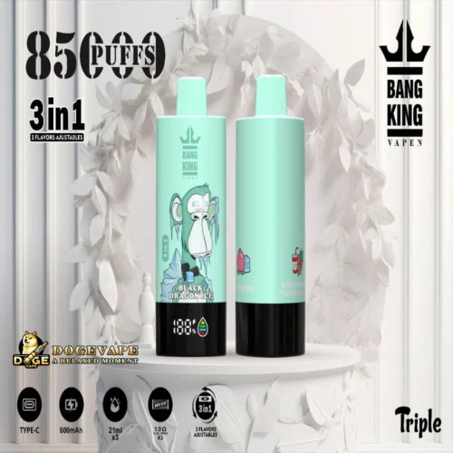 Two Mint Green Bang King Vape Devices With Black Bases Displayed On A White Round Table, Featuring A Frozen Gorilla Design On Front With 'Black Dragon Ice' Text, And Icons Showing 85,000 Puffs, 3-In-1 Adjustable Flavours, 600Mah Battery, And 21Ml Capacity, Set Against A White Floral Backdrop With Bang King Logo And Dogevape Branding.