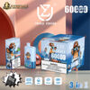Blue disposable vape device and packaging featuring a cartoon monkey wearing sunglasses and a red patterned headband, labeled UZY with 6000 puffs, triple flavor (summer peach, strawberry ice, blue razz ice), with warning about nicotine content, displayed on a table against a modern geometric background.