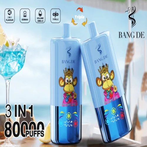 Promotional Image Showcasing Two Blue Bang De Vaping Devices With A Cartoon Monkey Wearing A Crown Design, Highlighting Features Like &Quot;3 In 1 Flavour,&Quot; &Quot;650Mah,&Quot; And &Quot;80000 Puffs,&Quot; Placed Beside A Tropical Cocktail Against A Beach Backdrop.